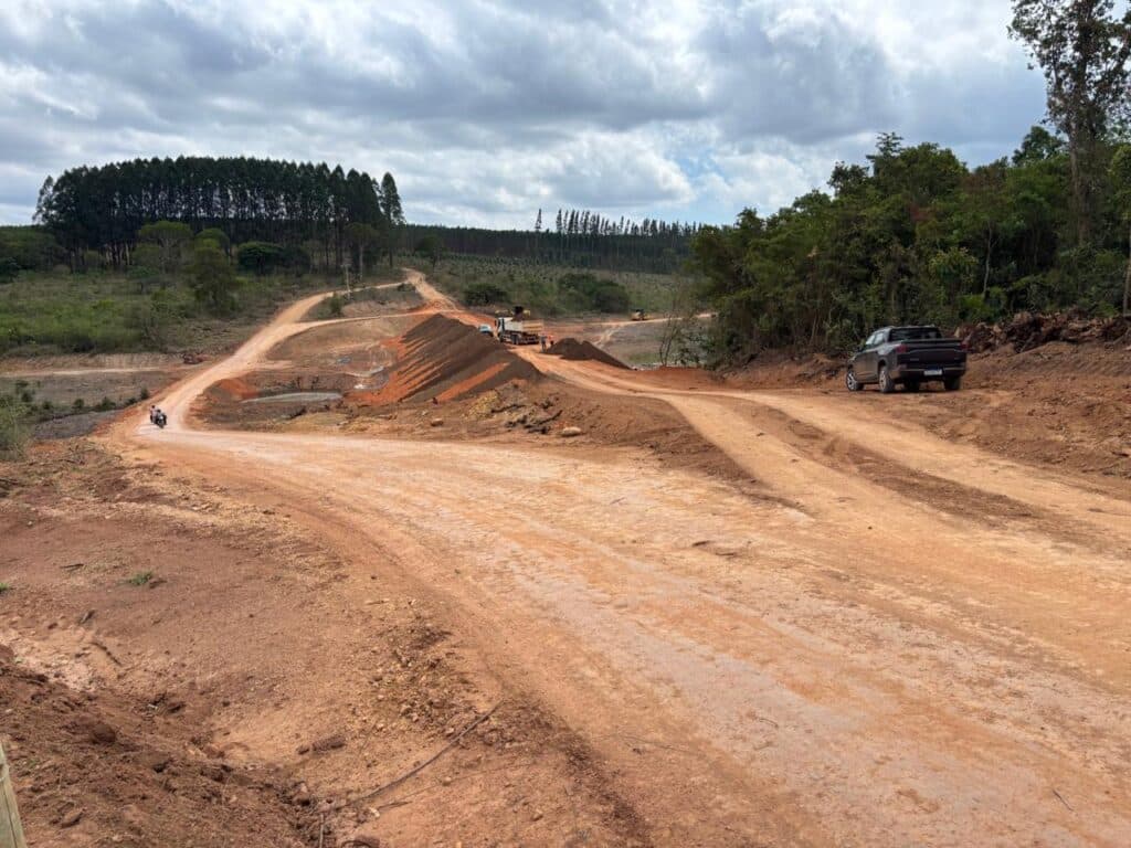 Registro de campo do alteamento e terraplenagem de uma via vicinal cercada por vegetação nativa.